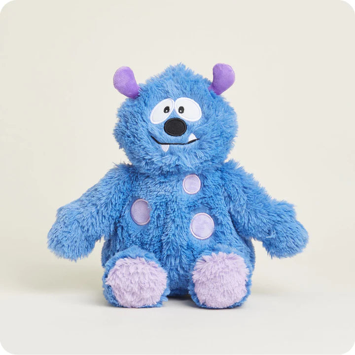 A soft, fuzzy blue plush monster toy with friendly eyes, small horns, and a wide smile, designed to be microwavable.