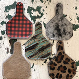 Cow tag-shaped leather and hair-on-hide reusable car freshener charm designed for re-scenting with oils.