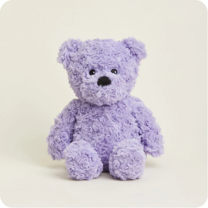 A soft, plush teddy bear with curly purple fur and a friendly face, designed to be microwavable.