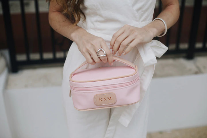 A rose Jon Hart mini makeup case with natural leather trim and a monogrammed patch.